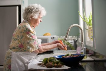 An elderly lady washing carrots.